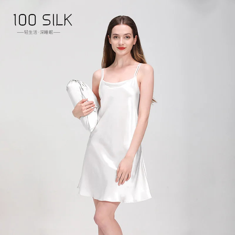 Woman wearing a white silk dress holding a white silk pillow on a gray background with '100 SILK' branding.