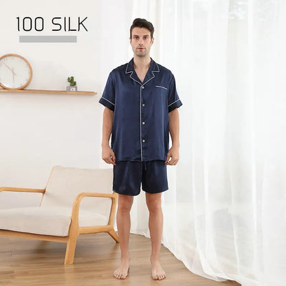 Man wearing navy silk pajama set in a room with a white curtain and wooden chair.
