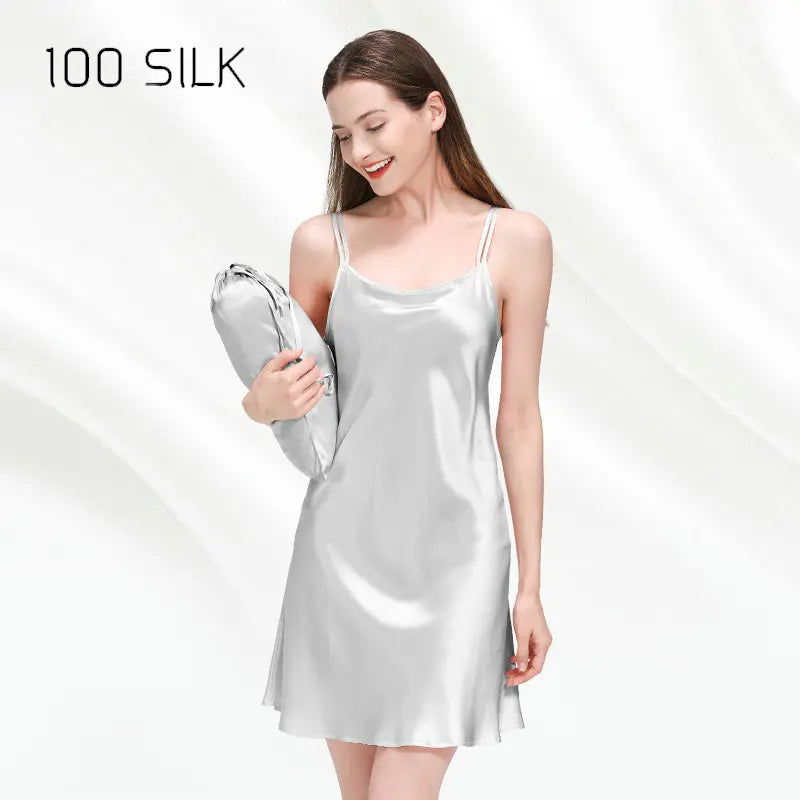 Woman wearing a silver satin slip dress holding a matching bag on a white background with '100 SILK' text.