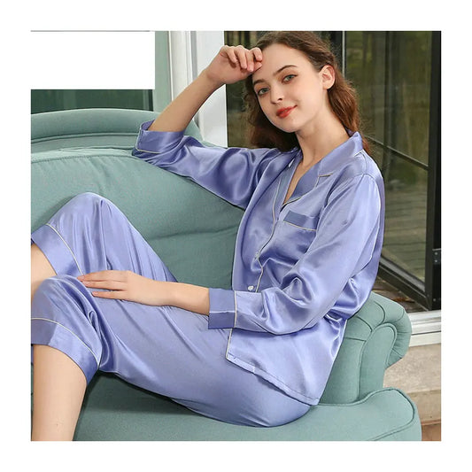 Woman wearing a light purple satin pajama set sitting on a green couch.