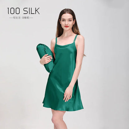 Woman wearing a green silk dress holding a matching bag on a gray background with '100 SILK' branding.
