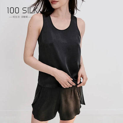 Woman wearing a black satin tank top and shorts with '100 SILK' branding.