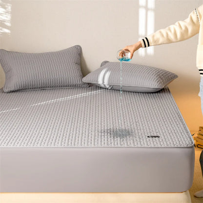 Person pouring water onto a gray quilted mattress cover on a bed.