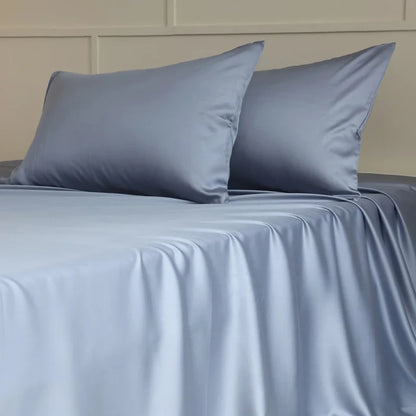 Gray satin sheet set with matching pillows on a bed.