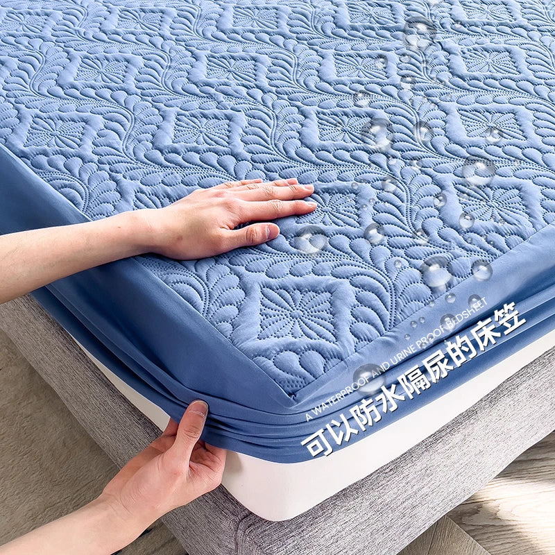 Blue quilted bed cover with floral pattern on a bed, held by hands.