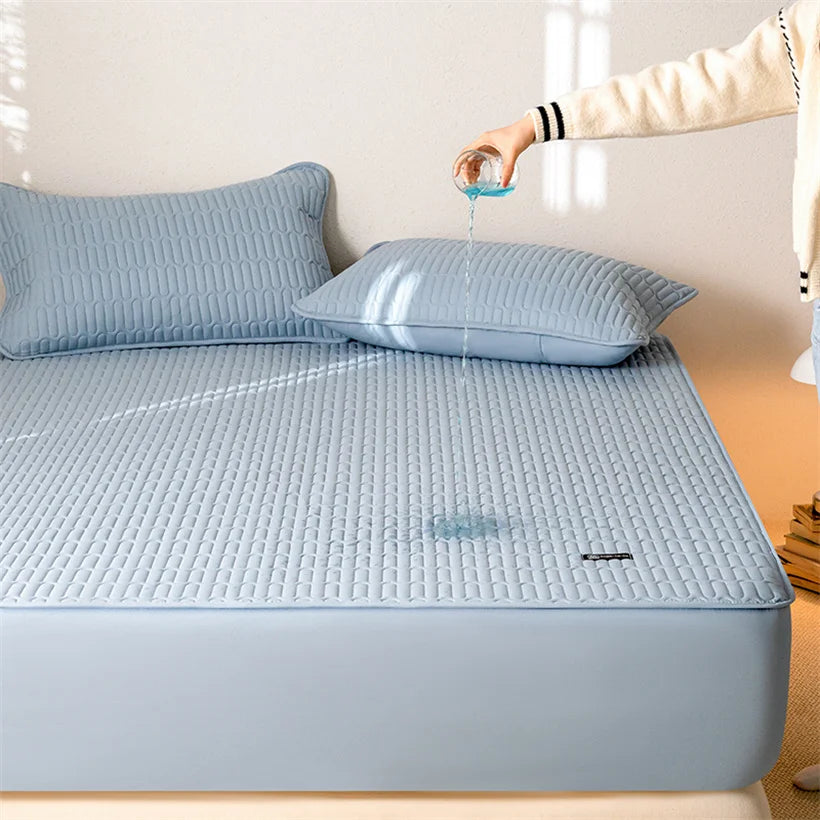 Blue quilted mattress cover on a bed with a hand pouring water onto it.