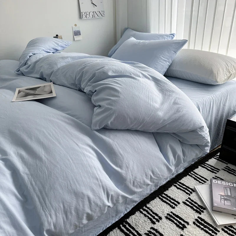Light blue bedding set on a bed with a white wall and decorative items in the background.