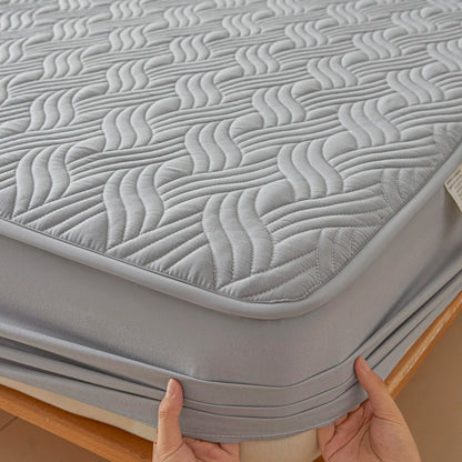 Gray mattress cover with wavy pattern held by hands on a wooden surface