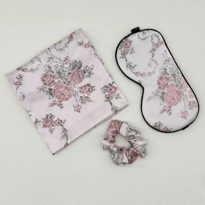Set of floral-patterned items including a pouch, eye mask, and scrunchie on a light gray background